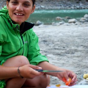 Forspaddling Nepal, en kvinnlig forsguide skär grönsaker på stranden